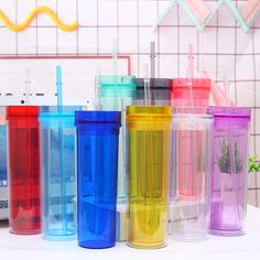 many different colored cups are lined up on the table with straws in each one