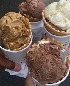 four ice creams in paper cups with different toppings