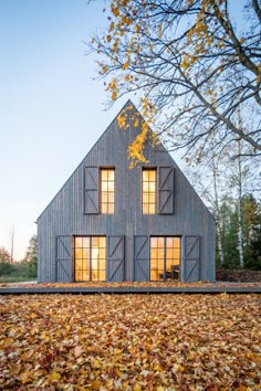 a house that is surrounded by leaves on the ground and trees in front of it