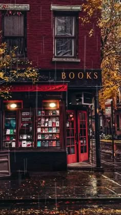 a red book store sitting on the side of a rain soaked street next to trees