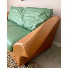 a green and brown couch sitting on top of a carpeted floor next to a wall