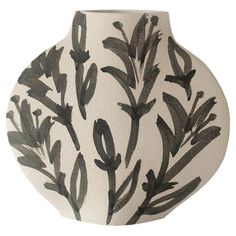 a black and white vase with leaves painted on it