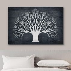 a white tree on a black and white wall above a bed with pillows in front of it