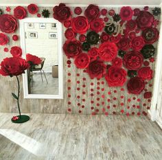 a room decorated with red paper flowers on the wall and a mirror in the corner