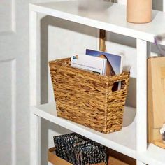 a wicker basket sits on top of a white book shelf filled with books and magazines