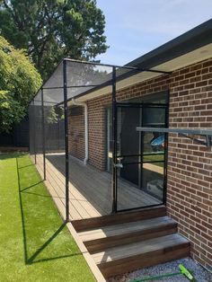 a fenced in porch with steps leading up to the back door and patio area