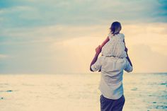 a man carrying a child on his back at the beach