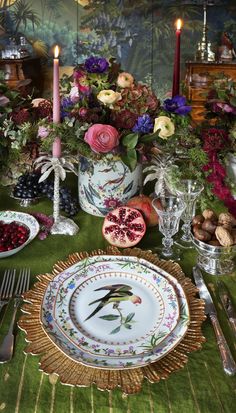 the table is set with flowers, fruit and candles