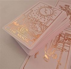 three playing cards with gold foil on them sitting next to each other, one has the moon in it's center