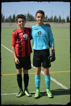 two young boys standing next to each other on a soccer field