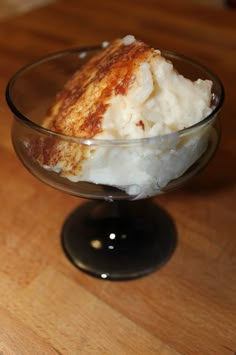 a glass bowl filled with ice cream on top of a wooden table