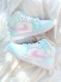 a pair of white and pink sneakers on top of a bed