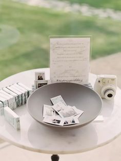 a table topped with a bowl filled with lots of cards next to a white camera