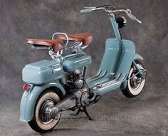 an old blue motorcycle is parked on a gray background with brown leather seat and handlebars