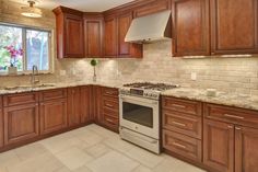 a kitchen with wooden cabinets and marble counter tops, along with a stainless steel stove top oven