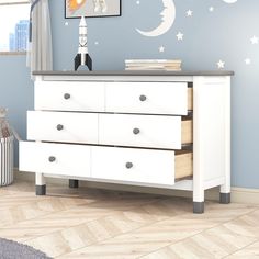 there is a dresser with drawers in the room that has stars and moon decals on it