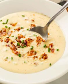 a white bowl filled with potato soup topped with bacon and green onion florets