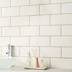 a bathroom sink sitting under a faucet next to a white counter top with soap dispensers on it