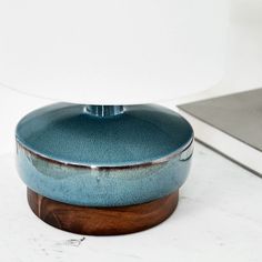 a blue dish sitting on top of a counter next to a white lamp and wooden base