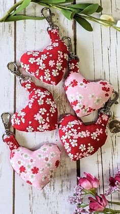 four heart shaped keychains with flowers on them sitting next to some pink and white flowers