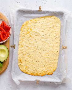 an uncooked pizza sitting on top of a cutting board next to sliced vegetables