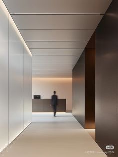 a person walking down a hallway in an office building with white walls and flooring