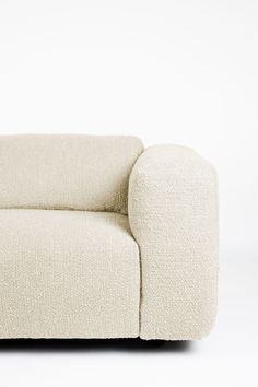 a white couch sitting on top of a white floor next to a wooden table and chair