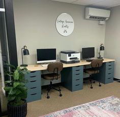 an office cubicle with two computers on the desk and a rug in front of it