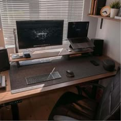 a computer desk with two monitors, keyboard and mouse on it in front of a window