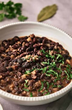 a white bowl filled with black beans and garnished with parsley on top