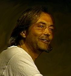 a man with long hair is smiling at the camera