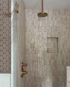 a bathroom with a shower head, toilet and tiled walls in beige tones that match the rest of the room