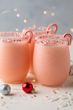 three glasses filled with pink liquid and sprinkles on top of a table