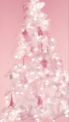 a pink christmas tree with white lights and ornaments