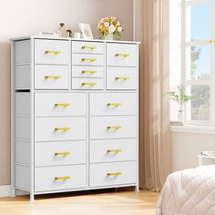 a white dresser with yellow handles and drawers