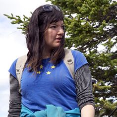 a woman holding a frisbee in her hand and wearing a blue shirt with stars on it