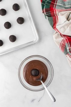 chocolate pudding in a glass bowl with a spoon next to it on a marble counter top