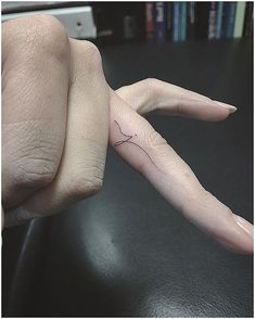 a person's hand with a tiny tattoo on it, holding the finger of another persons hand