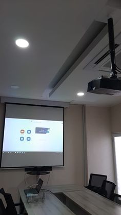 a conference room with a projector screen and chairs