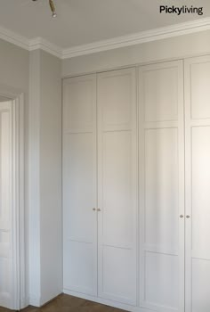 an empty room with white closets and wood flooring