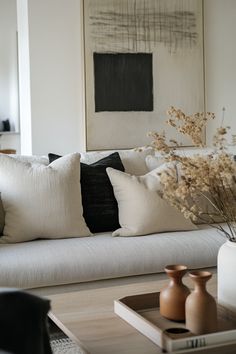 a living room filled with lots of white furniture and pillows on top of a couch