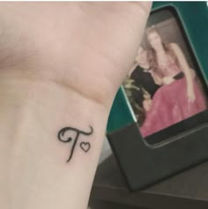 a woman's wrist tattoo with the letter f on her left hand and an image of a couple