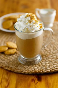 there is a cup of coffee with whipped cream in it and cookies on the side