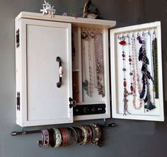 a white cabinet filled with lots of bracelets and necklaces hanging from it's sides