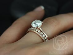 a woman's hand with a diamond ring on top of her finger and the other hand holding an engagement ring