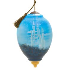 a blue glass ornament with a castle in the sky on it's side