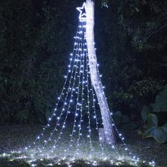 a lighted christmas tree in the middle of some grass