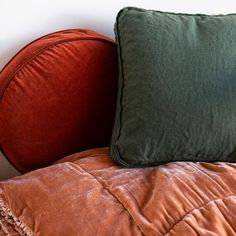 a bed with two pillows on top of it and a pillow in the corner next to it