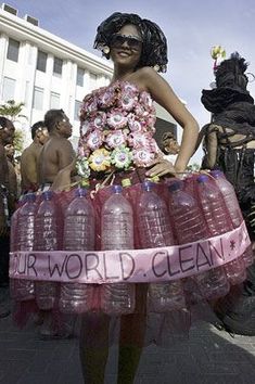 a woman in a dress made out of plastic bottles with words written on the side