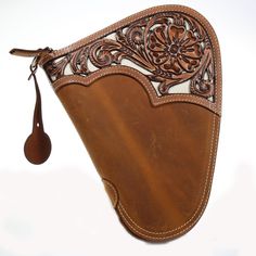 a brown leather case with an ornate design on the side and a tassel hanging from it